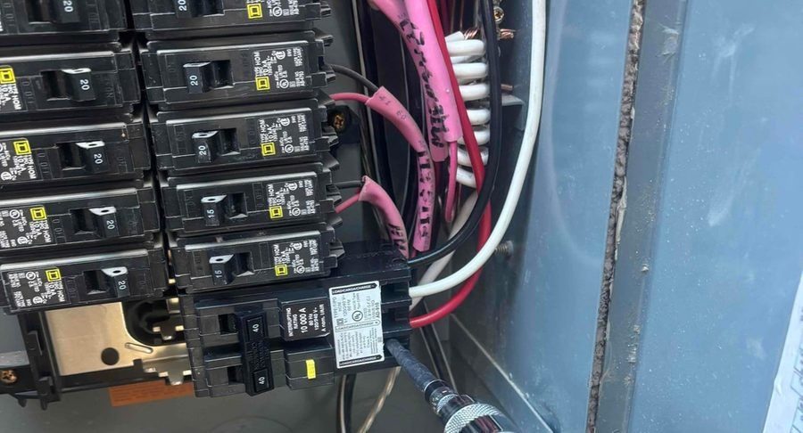 A close-up view inside an electrical breaker panel shows rows of black circuit breakers with labeled switches (15 and 20 amps).