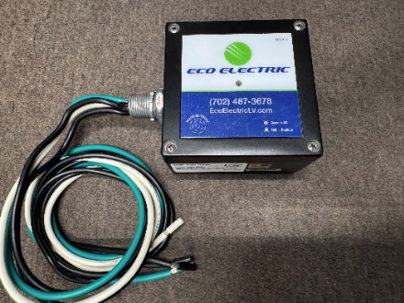 Black Eco Electric control box with a blue label, wired cables (teal, white, black) extending from it on a carpeted surface.