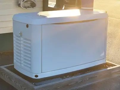 White portable generator mounted on a wooden platform outdoors beside a building