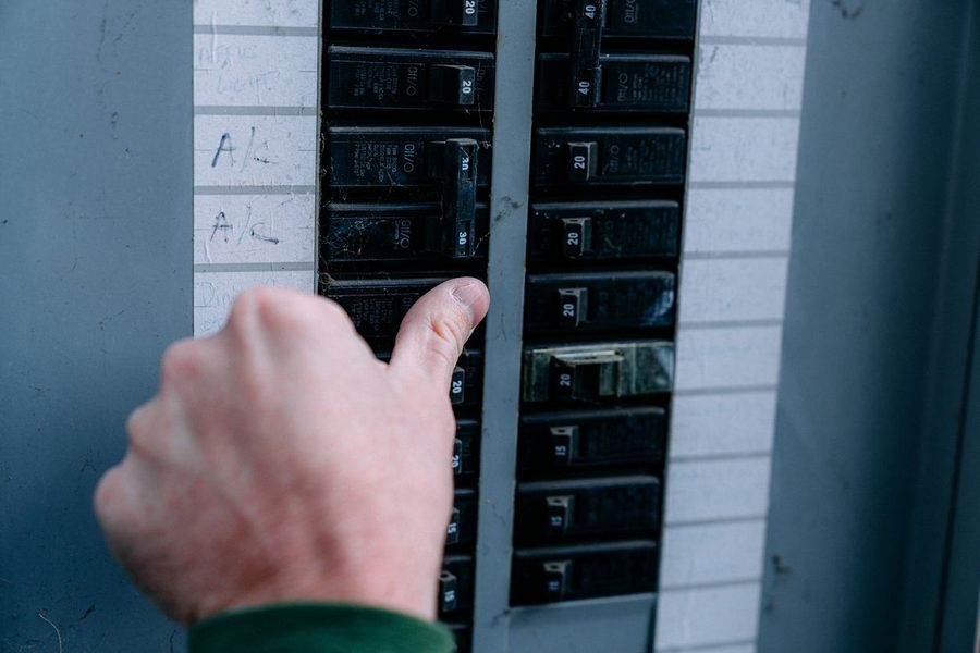 Electrician testing and checking an electrical panel. He is using his thumb to flip the switch.
